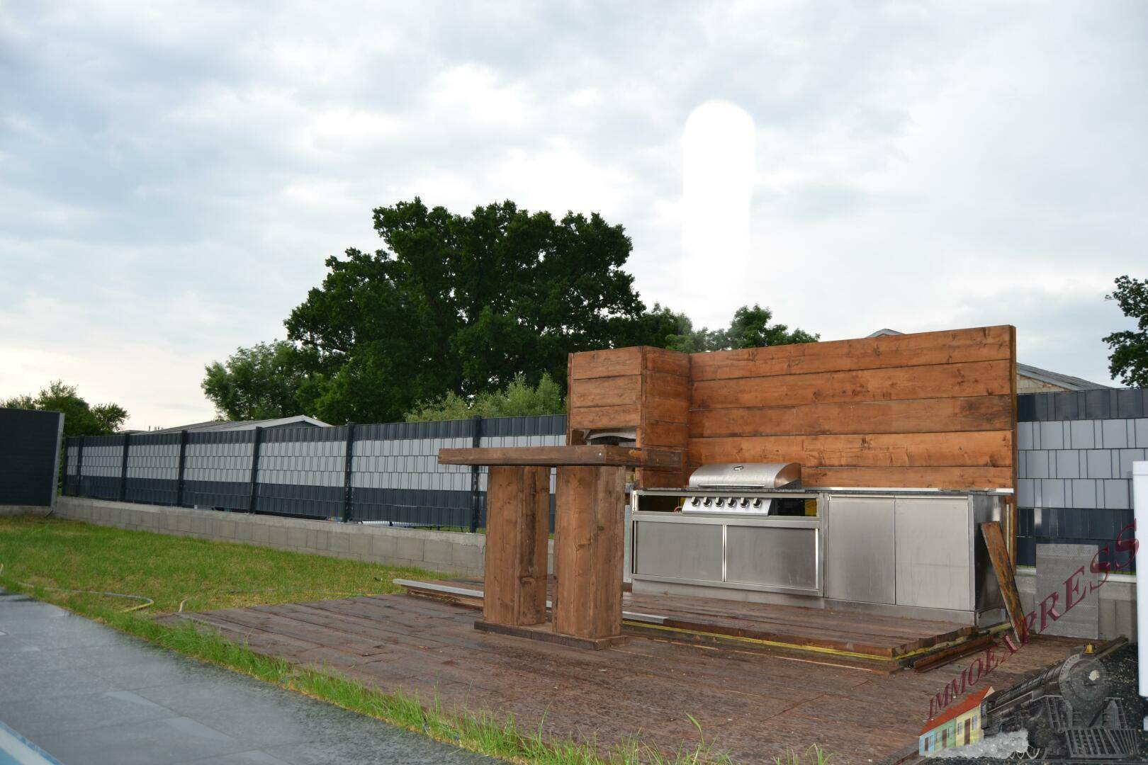 Detailansicht der modernen Outdoor-Küche mit Grill und Arbeitsflächen aus Edelstahl im Gartenbereich.