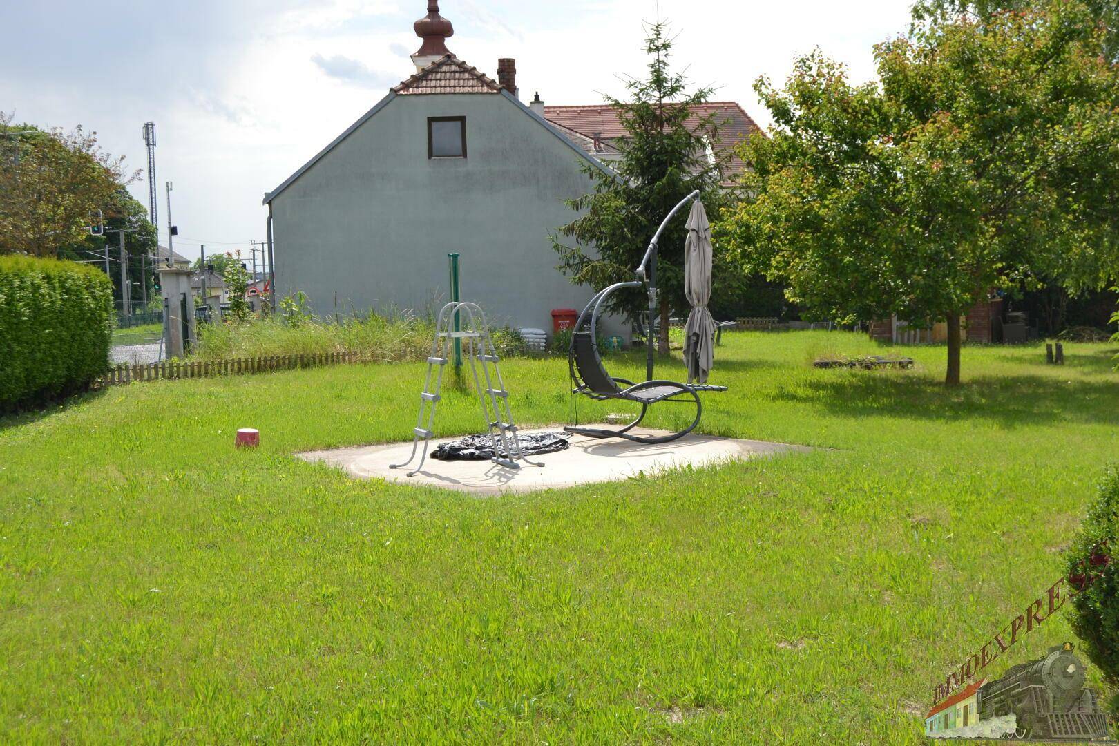 Große Rasenfläche im Garten mit einer Schaukel und einem Sonnenschirmgestell.
