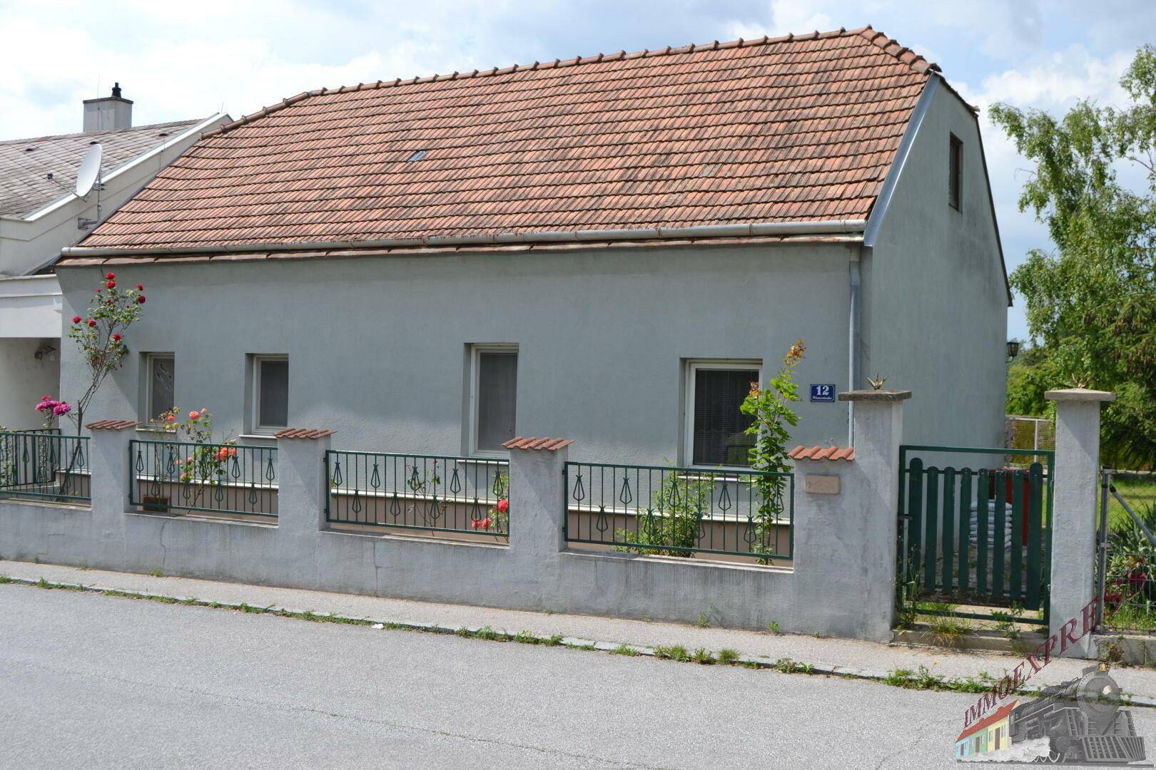 Fassade eines Einfamilienhauses mit Ziegeldach und kleinen Fenstern zur Straße hin.