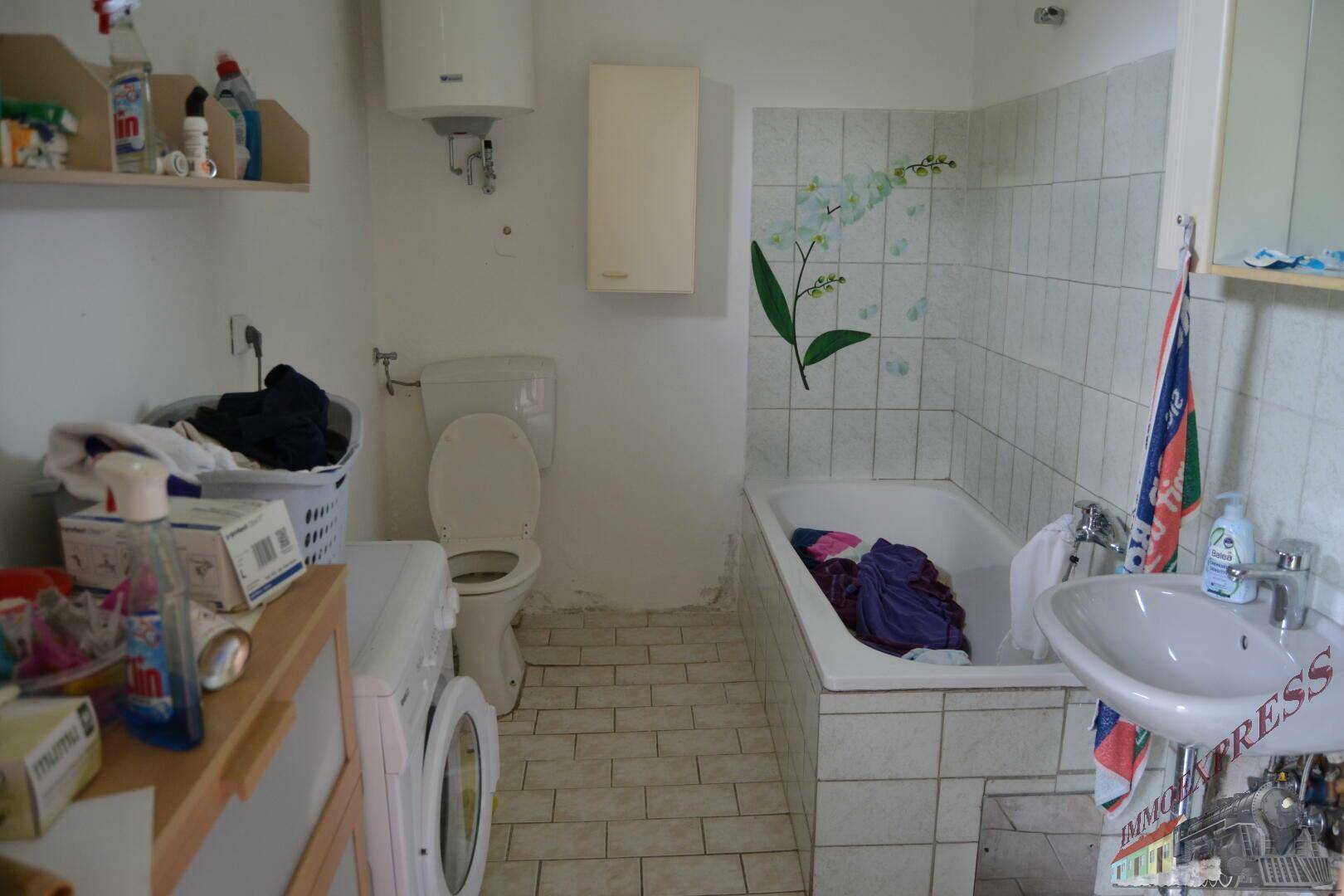 Badezimmer mit Badewanne, Toilette, Waschbecken und Fliesen an Wänden und Boden.