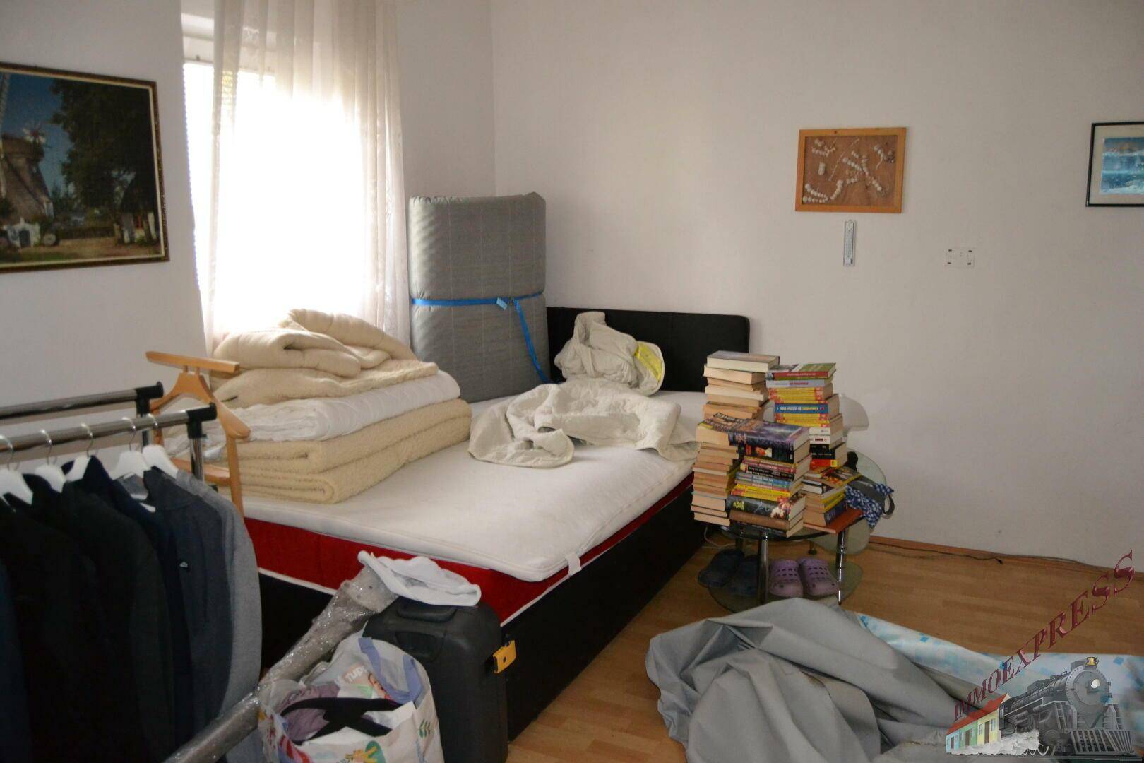 Schlafzimmer mit hellem Parkettboden, einem Bett und einem Fenster für natürliches Licht.