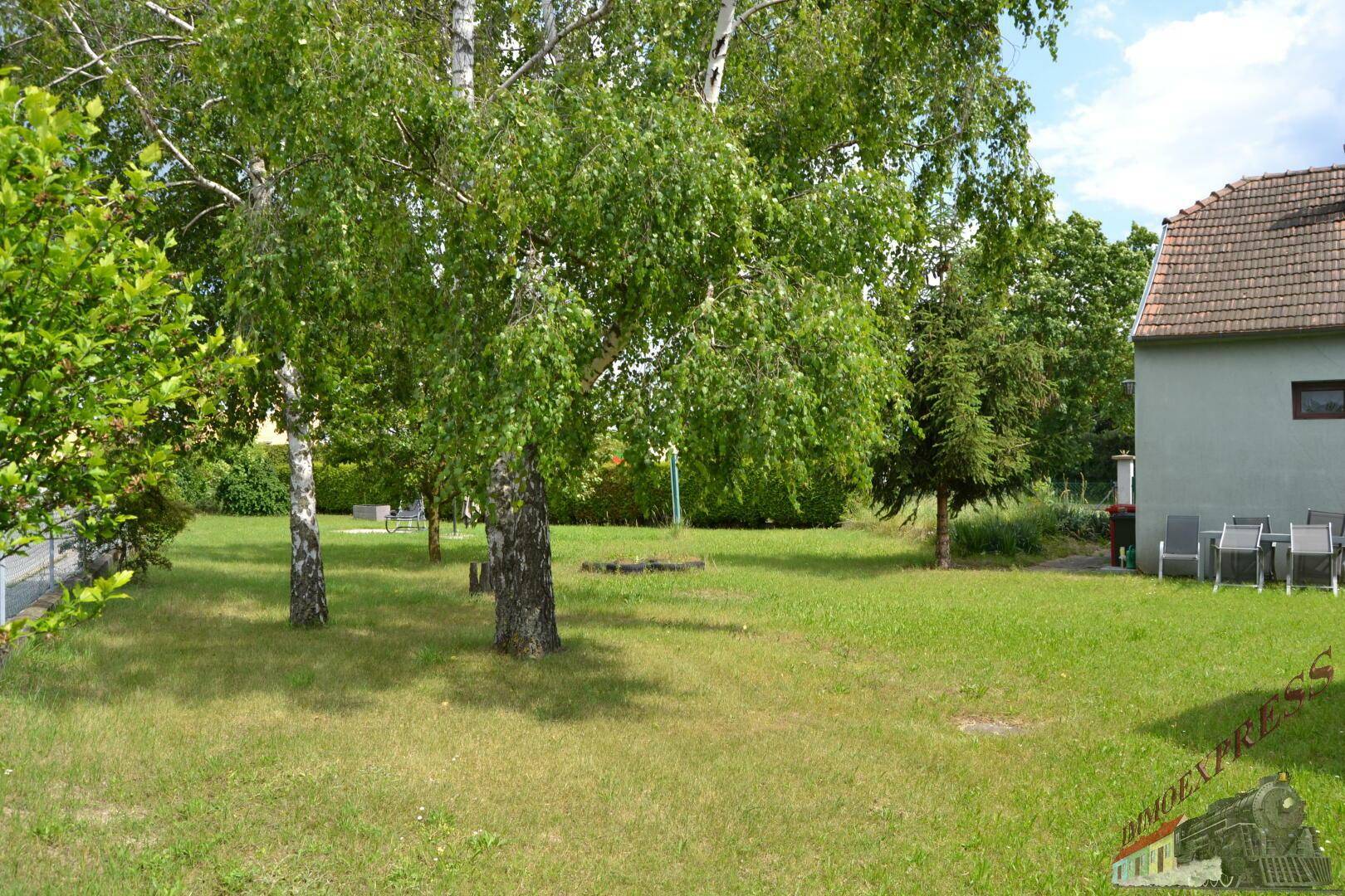 Weitläufiger Garten mit großen Bäumen und gepflegter Rasenfläche neben dem Haus.