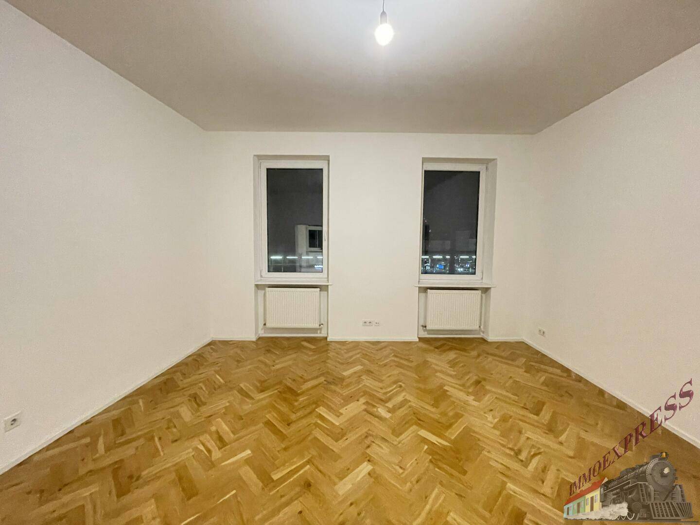 Heller Raum mit Fischgrätparkett und zwei Fenstern, bereit zur individuellen Gestaltung.