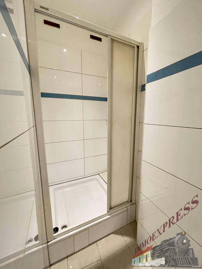 Duschbereich im Badezimmer mit weißen Fliesen und Glasschiebetür.
