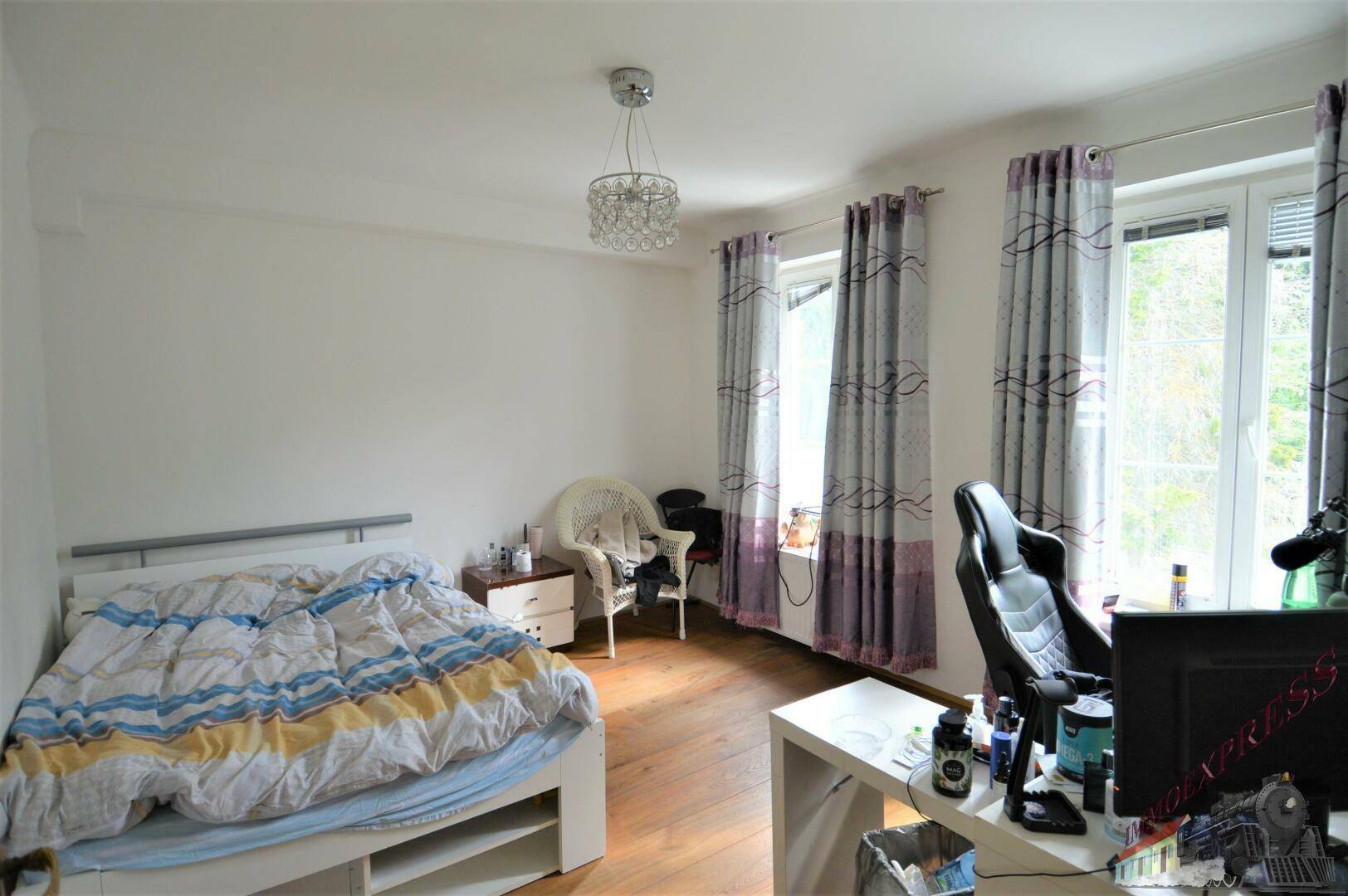 Helles Schlafzimmer mit Holzboden, Bett und Fenster, funktional eingerichtet.