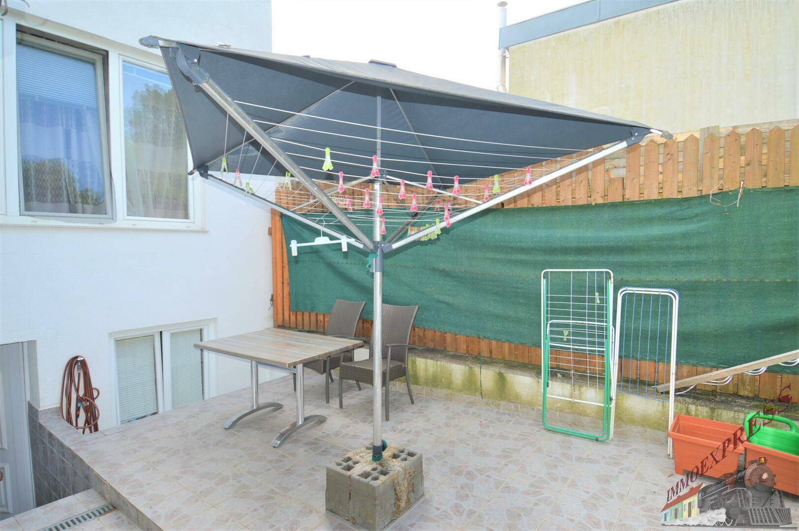 Gepflasterte Terrasse mit Wäschespinne und Gartenmöbeln, ideal für den Außenbereich.