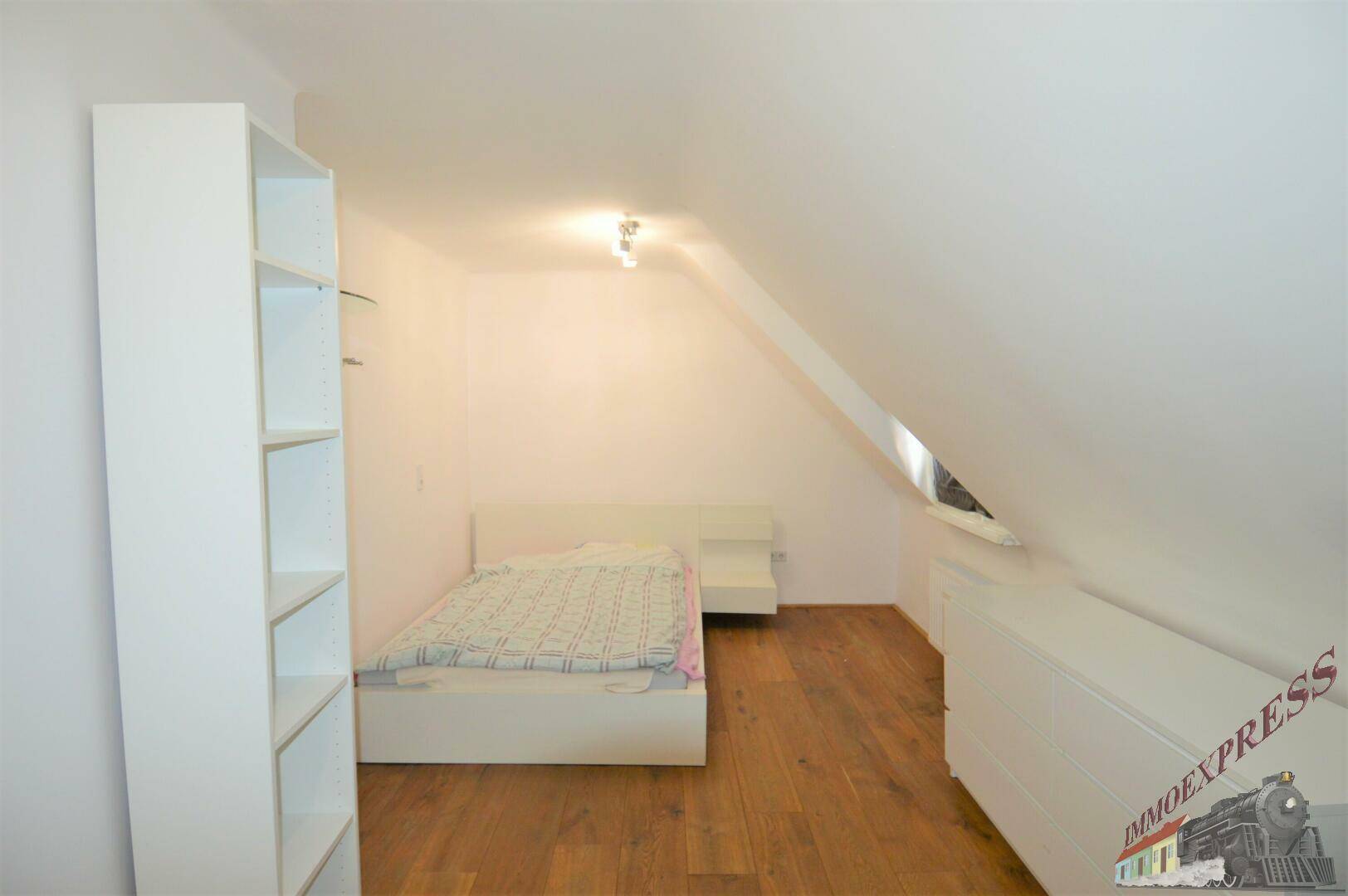 Dachgeschoss-Schlafzimmer mit Holzboden, Bett und Dachschrägen, hell und gemütlich.