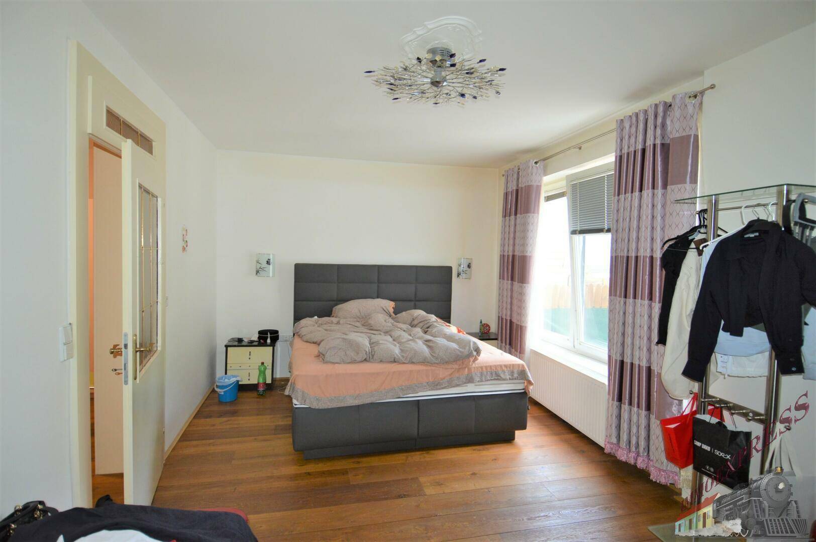 Schlafzimmer mit Holzboden, Doppelbett und großem Fenster mit Blick nach draußen.
