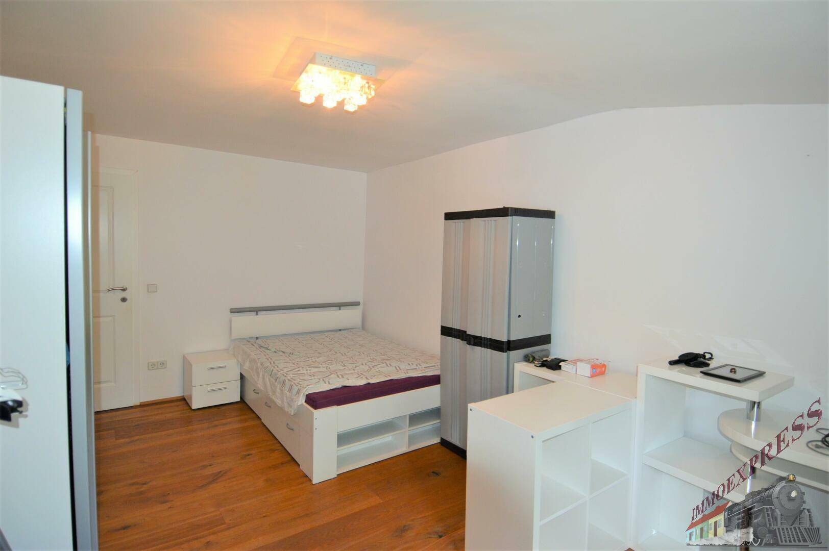 Schlafzimmer mit Holzboden, Bett und Schränken, funktional und hell gestaltet.