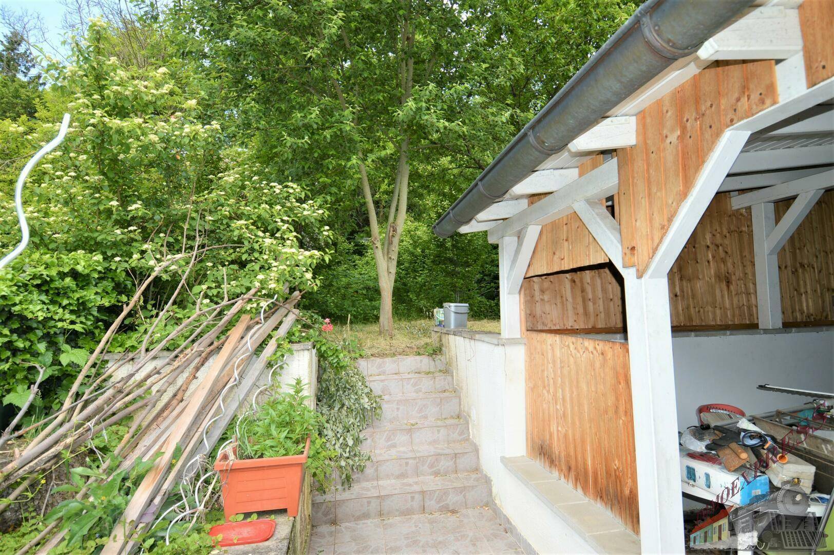 Steintreppe führt durch den Gartenbereich zu einer Holzkonstruktion im Grünen.