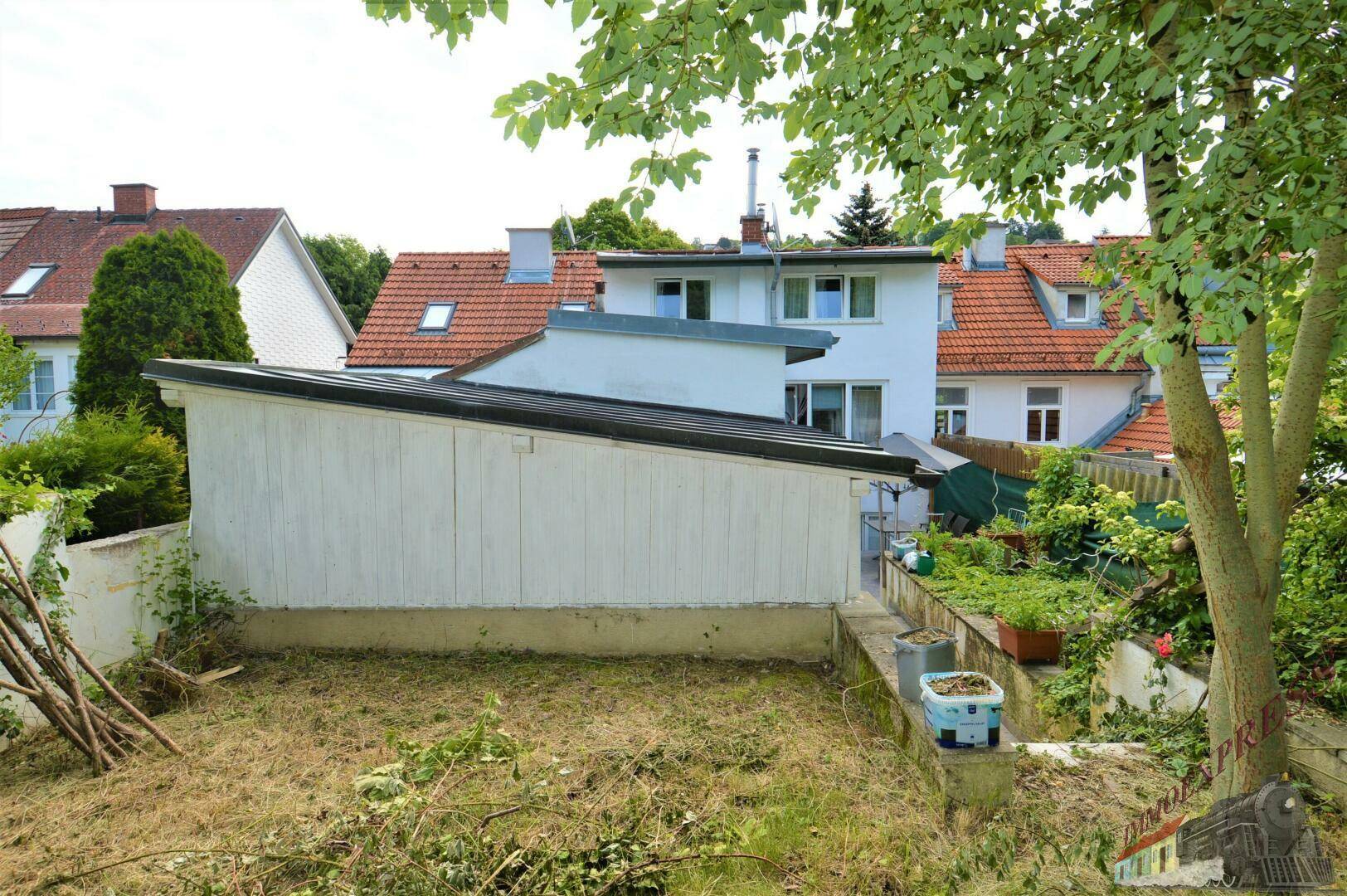 Gartenbereich hinter dem Haus mit Rasenfläche und Blick auf die umliegende Bebauung.