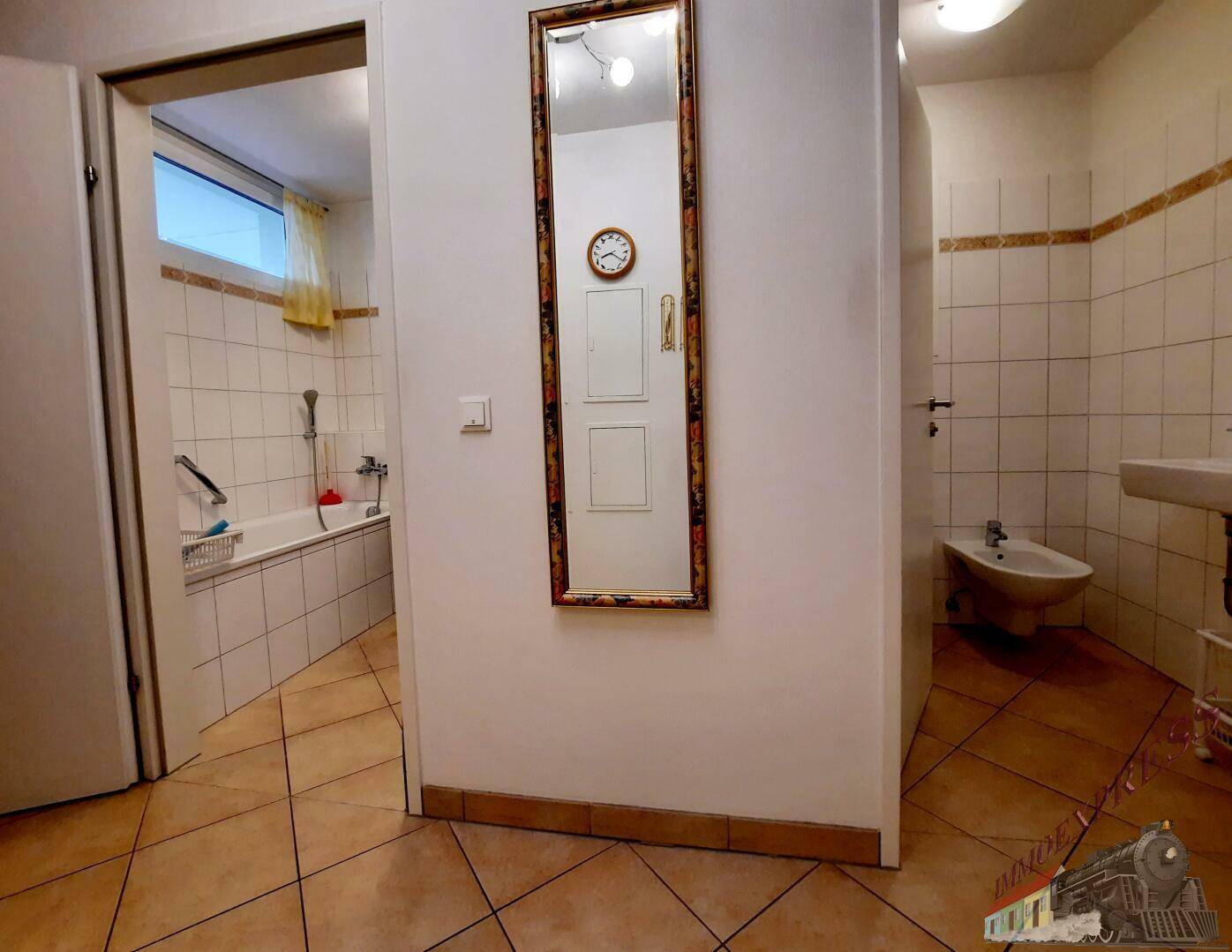 Flur mit Spiegel, der zum Badezimmer mit Badewanne und Bidet führt.