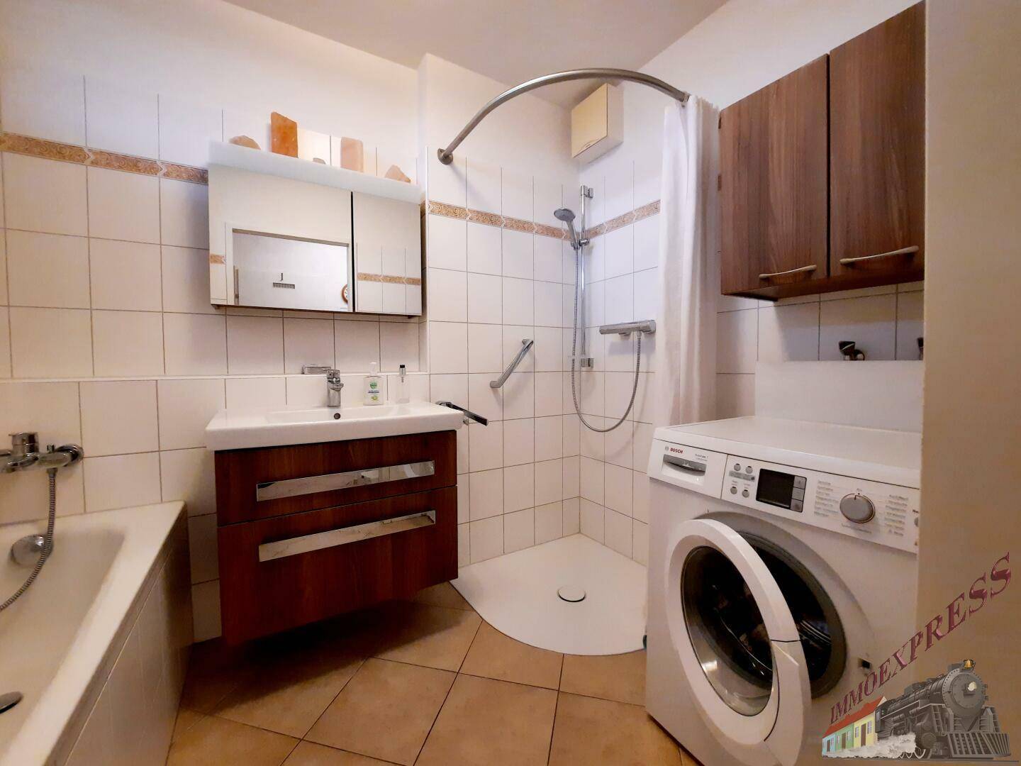 Badezimmer mit Dusche, Waschmaschine, Waschbecken und Spiegelschrank.