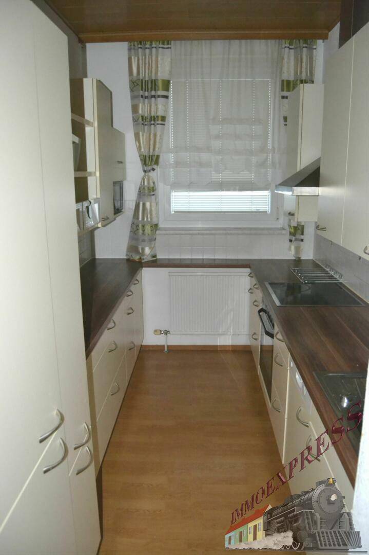 Schmale Küche mit Einbauschränken, Holz-Arbeitsplatten und Fenster für Tageslicht.