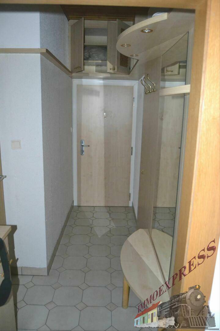 Heller Flur mit Fliesenboden, Garderobe und Spiegel, der zum Eingangsbereich führt.