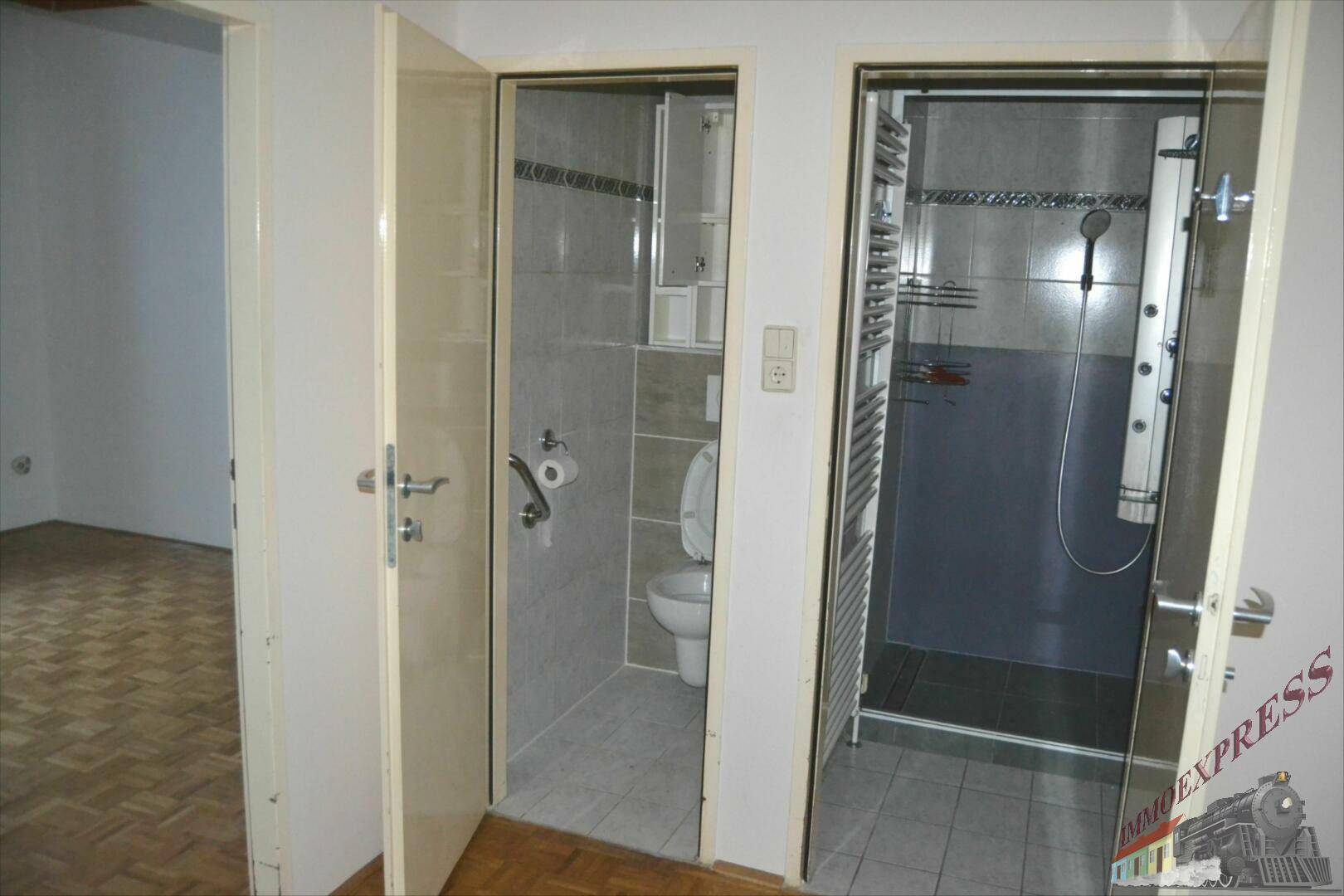 Badezimmer mit separatem WC und moderner Duschkabine, alles hell gefliest.
