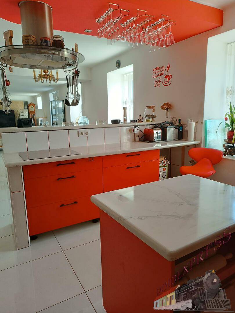 Moderne Küche mit leuchtend orangefarbenen Schränken, Kochinsel und Marmorarbeitsplatten.