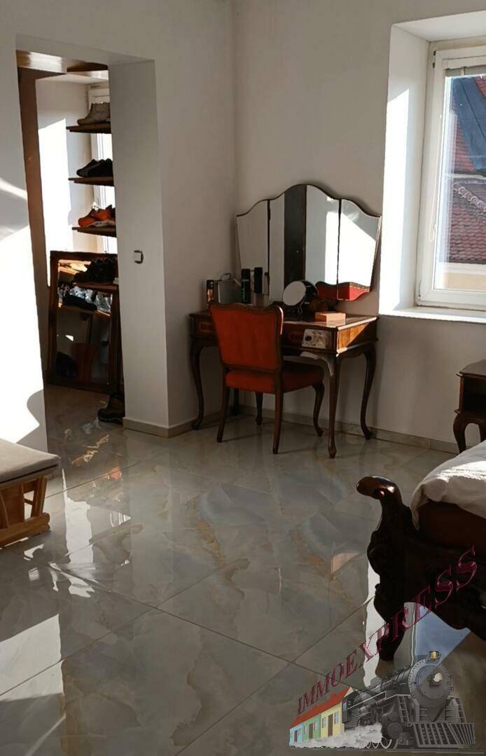 Helles Schlafzimmer mit Schminktisch und offenem Zugang zu einem Ankleidebereich.