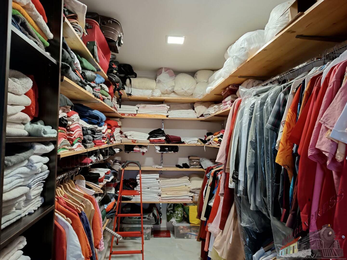 Geräumiger begehbarer Kleiderschrank mit Regalen und Kleiderstangen für viel Stauraum.