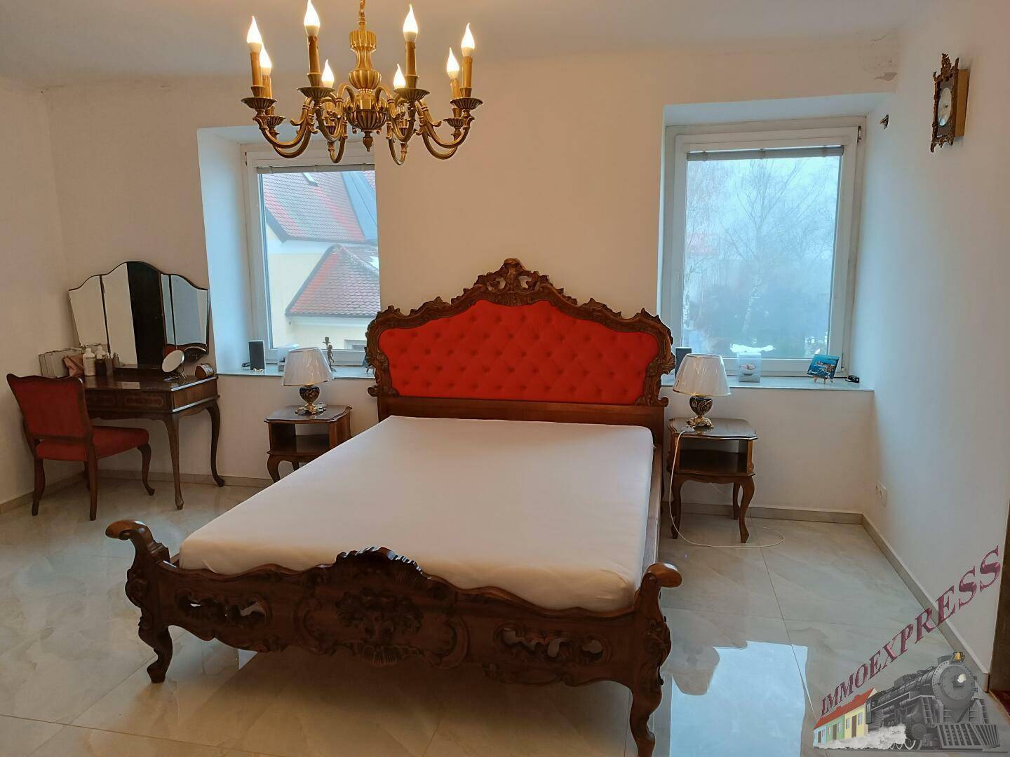 Elegantes Schlafzimmer mit großem Bett, antiken Möbeln und glänzenden Fliesen.