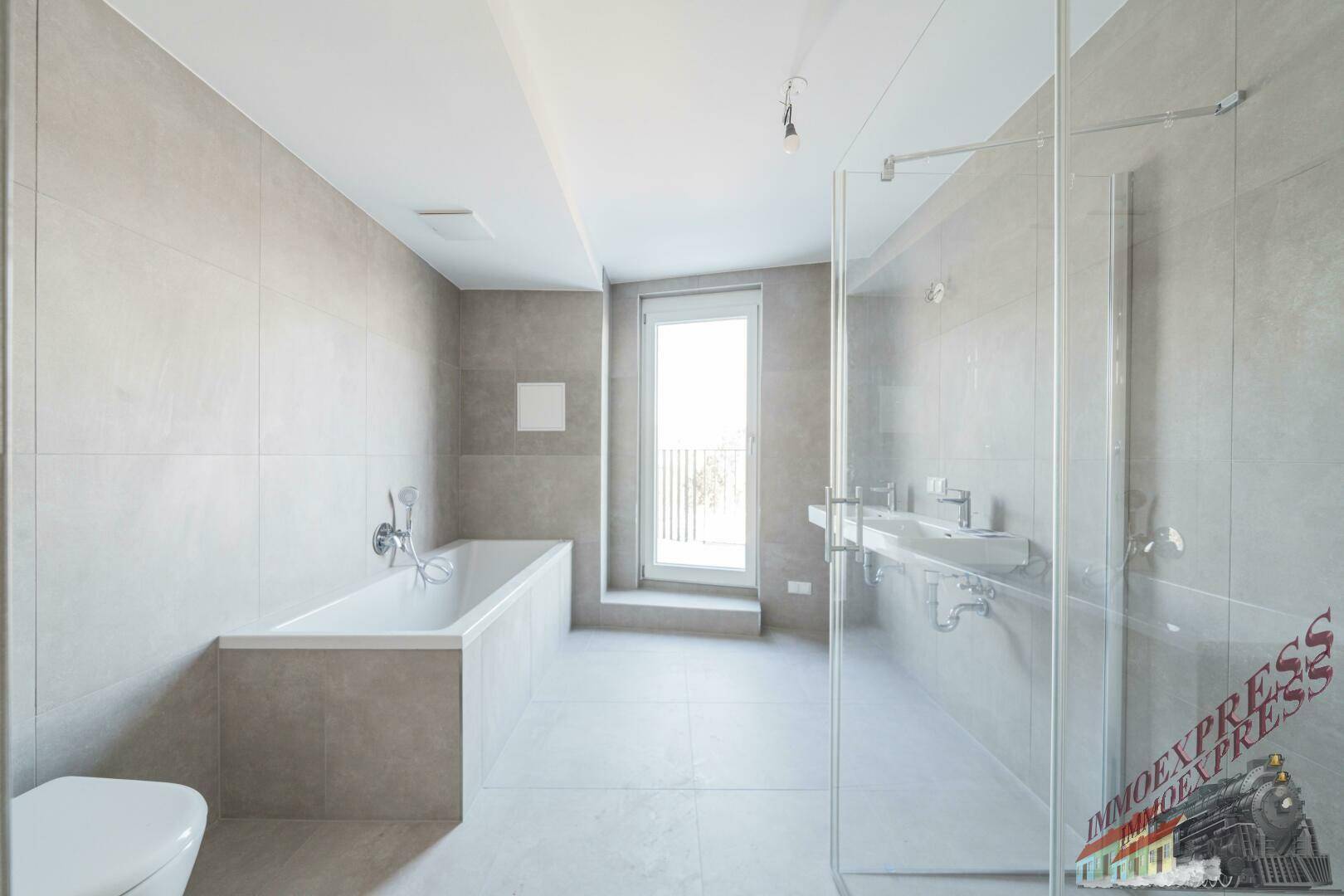 Modernes Badezimmer mit Badewanne, Dusche und WC, hell gefliest.