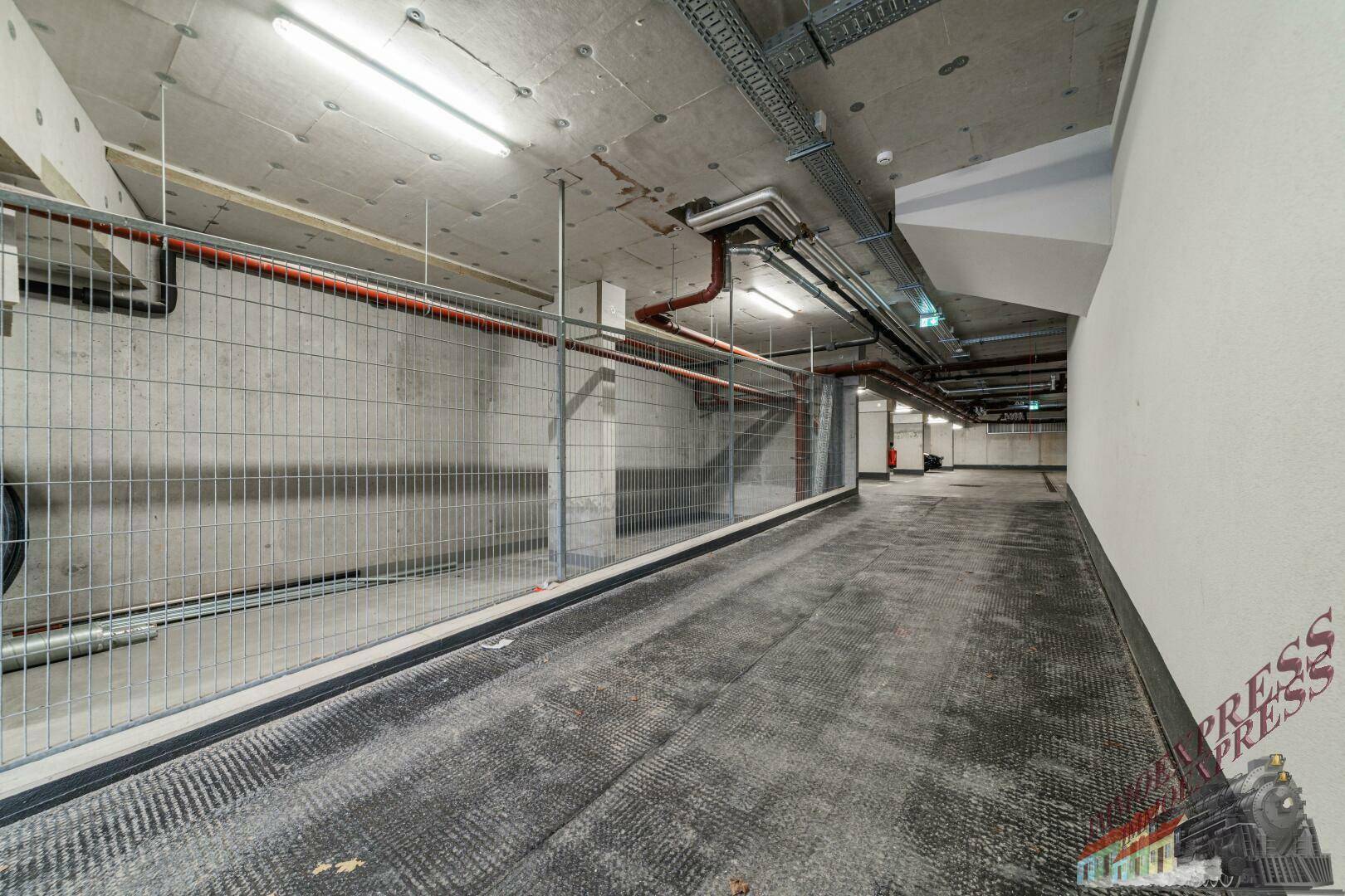 Tiefgarage mit Gitterabtrennungen und sichtbaren Rohren an der Decke.