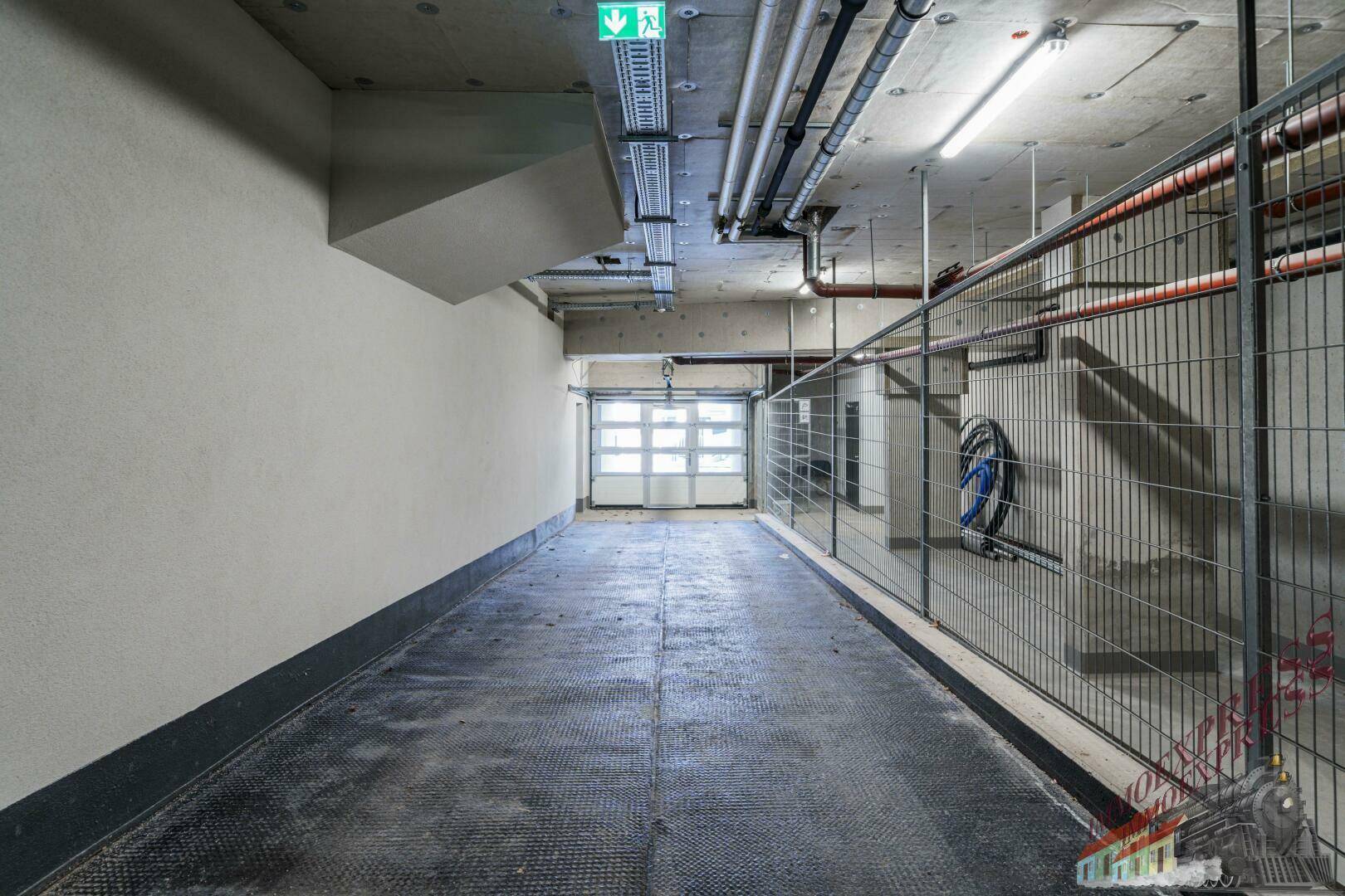 Zufahrt zur Tiefgarage mit Rolltor und Gitterabtrennungen.