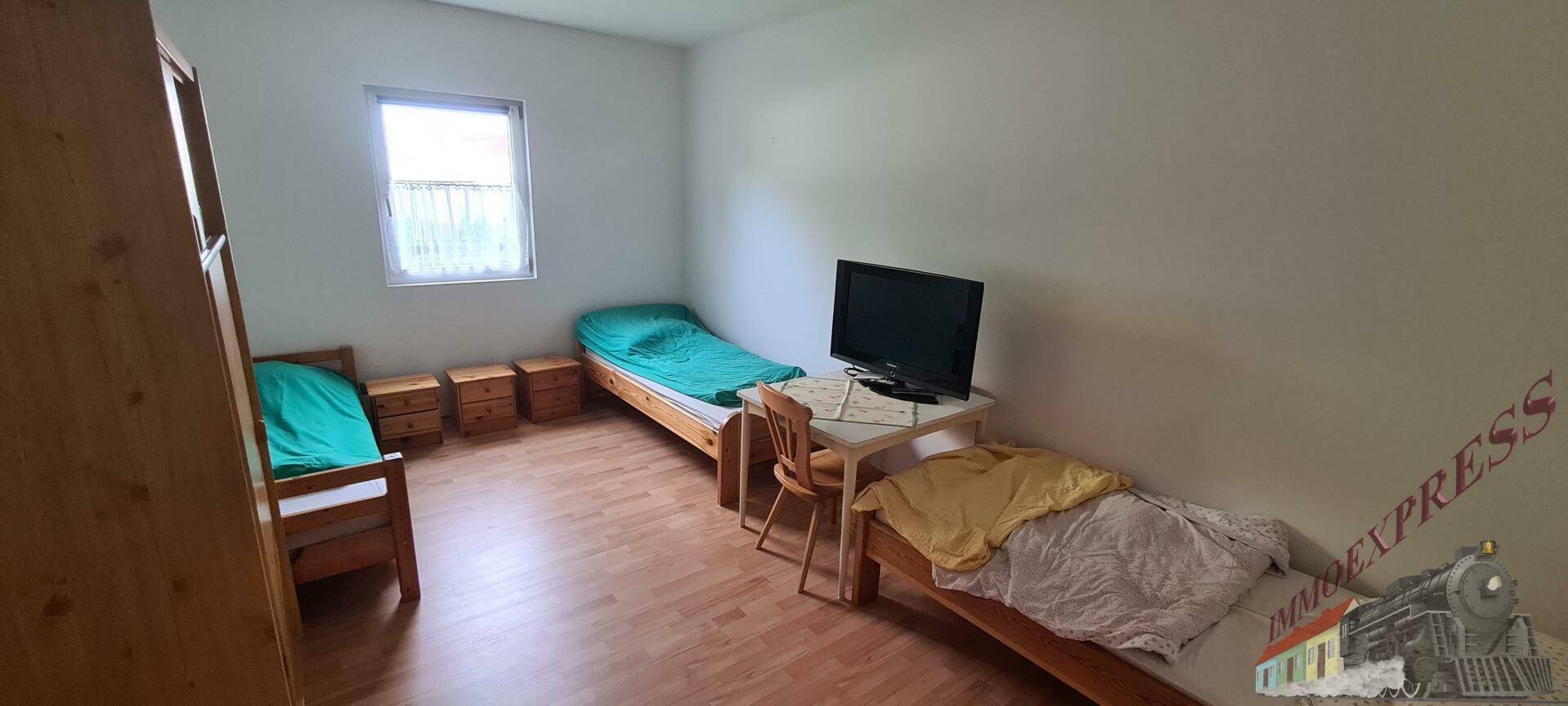 Schlafzimmer mit zwei Einzelbetten, Nachttischen, Fernseher und Fenster, auf Laminatboden.