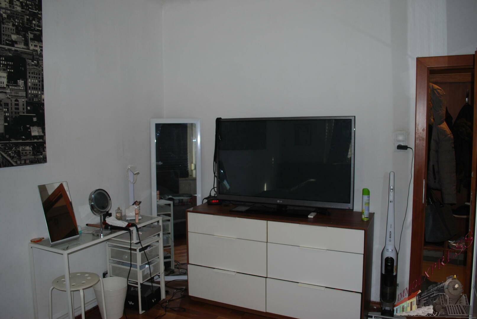 Schlafzimmer mit Fernseher auf einer Kommode und einem separaten Schminktisch.