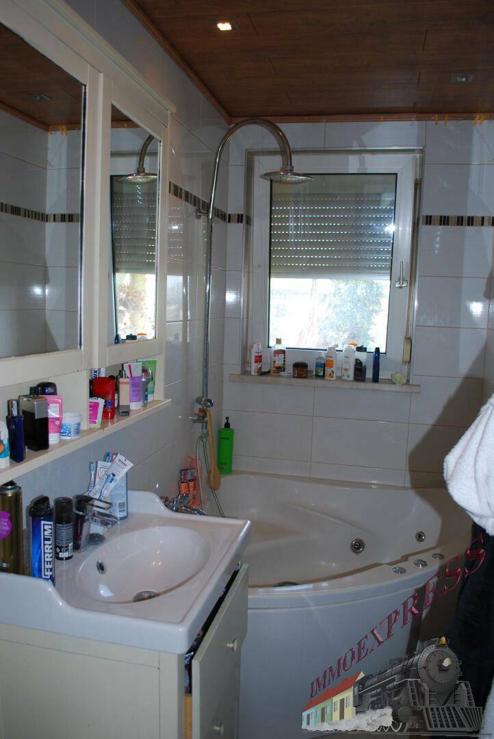 Badezimmer mit Eckbadewanne, integrierter Dusche, Einzelwaschbecken und Fenster.