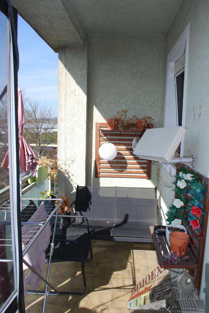 Sonnenverwöhnter Balkon mit Wäscheständer, Sitzgelegenheiten und Blick ins Grüne.