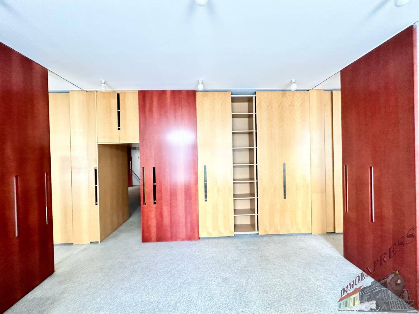 Großer Raum mit einer Wand aus Holzschränken und roten Schiebetüren, bietet viel Stauraum.