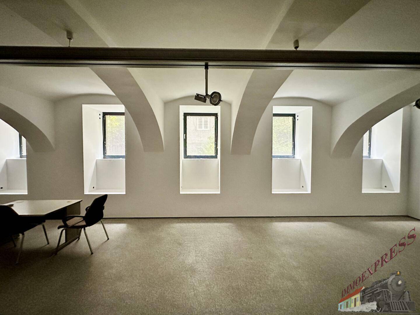 Großer, offener Raum mit gewölbten Decken und mehreren Fenstern, ideal für Büros oder Ausstellungsflächen.