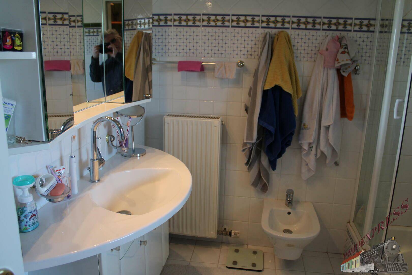 Badezimmer mit Waschbecken, Spiegelschrank, Bidet und Handtuchheizkörper.