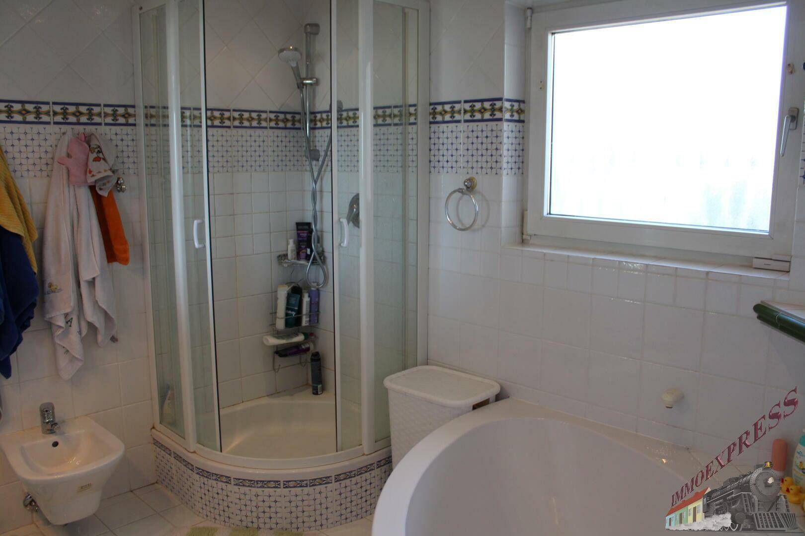 Geräumiges Badezimmer mit Duschkabine, Badewanne, Bidet und Fenster.
