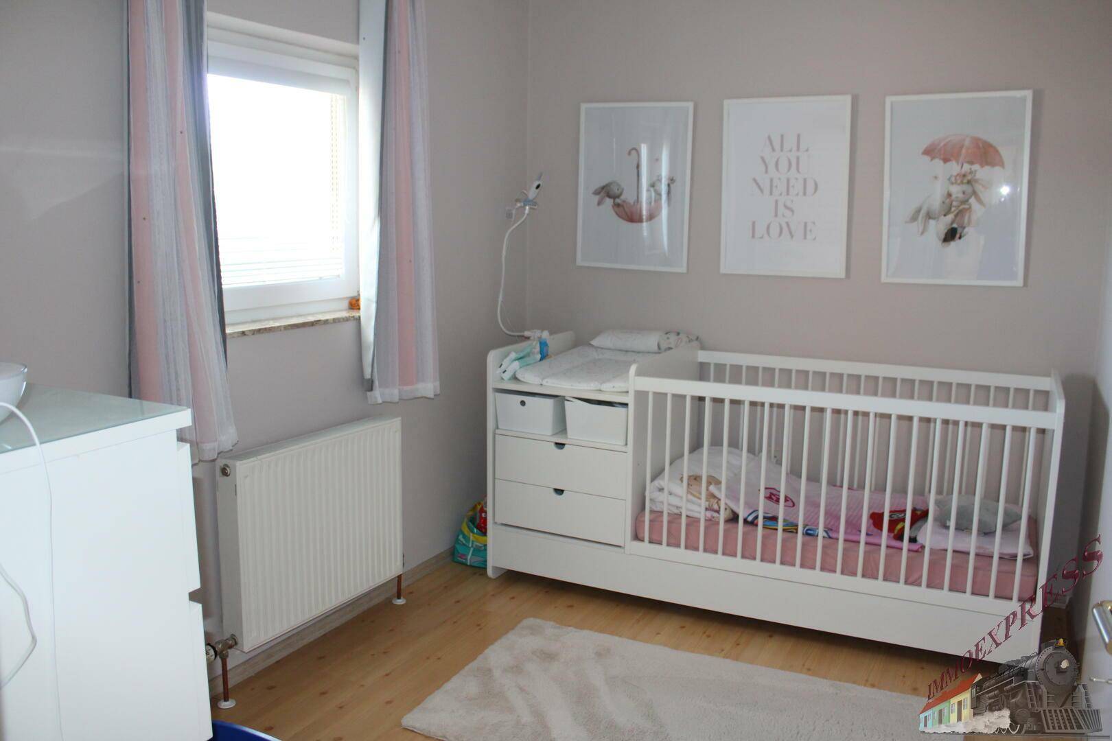 Kinderzimmer mit weißem Babybett, Wickeltisch und liebevoller Wanddekoration.