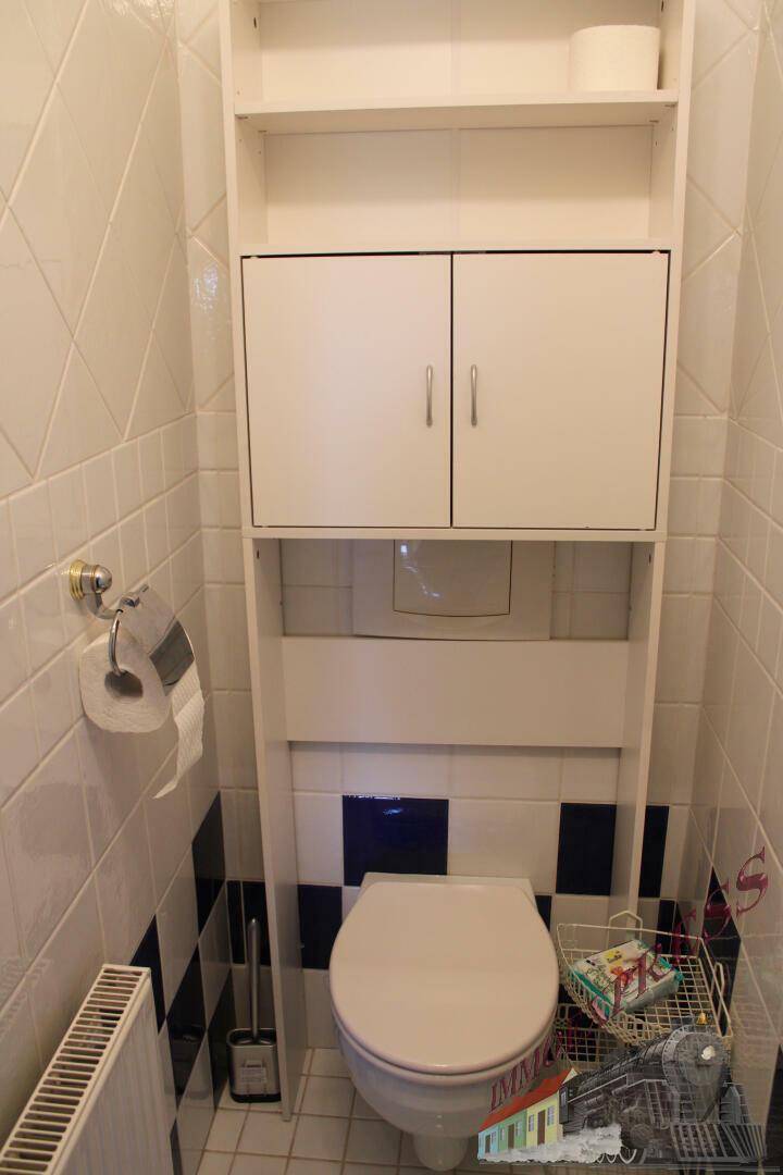 Separate Toilette mit Wand-WC und praktischem Regal für Stauraum.