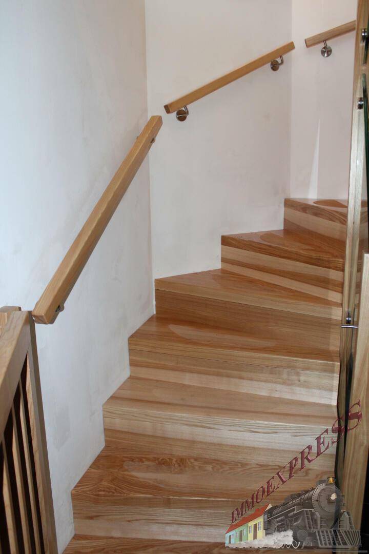 Heller Treppenaufgang mit Holzstufen und passendem Holzgeländer in modernem Design.
