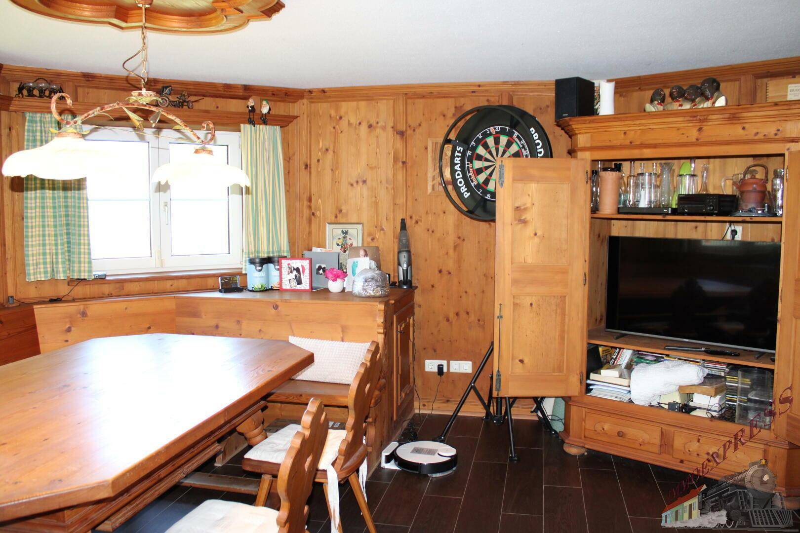Traditioneller Essbereich mit Holztäfelung, Eckbank und einem Schrank mit Fernseher.