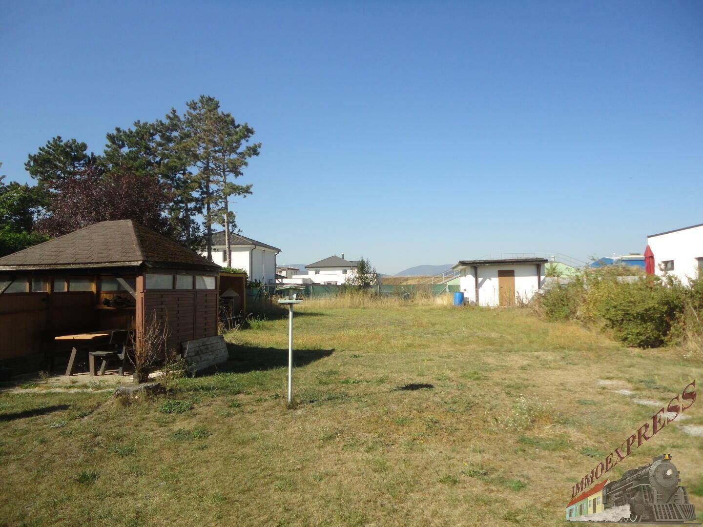 Weitläufiges Grundstück mit Wiese, einem Holzpavillon und Blick auf die Umgebung.