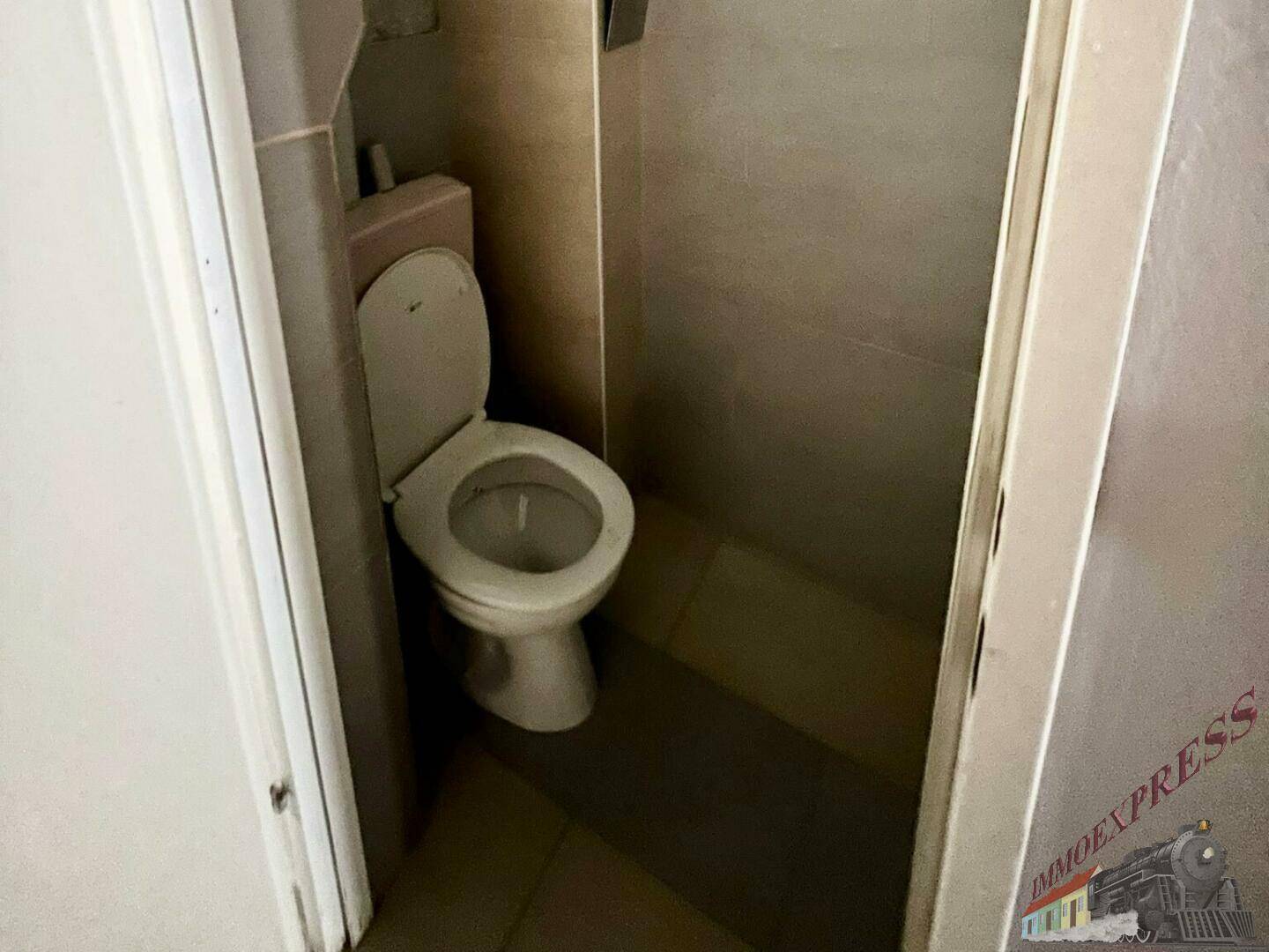 Kleine Toilette mit WC und hellen Fliesen, funktional und sauber.