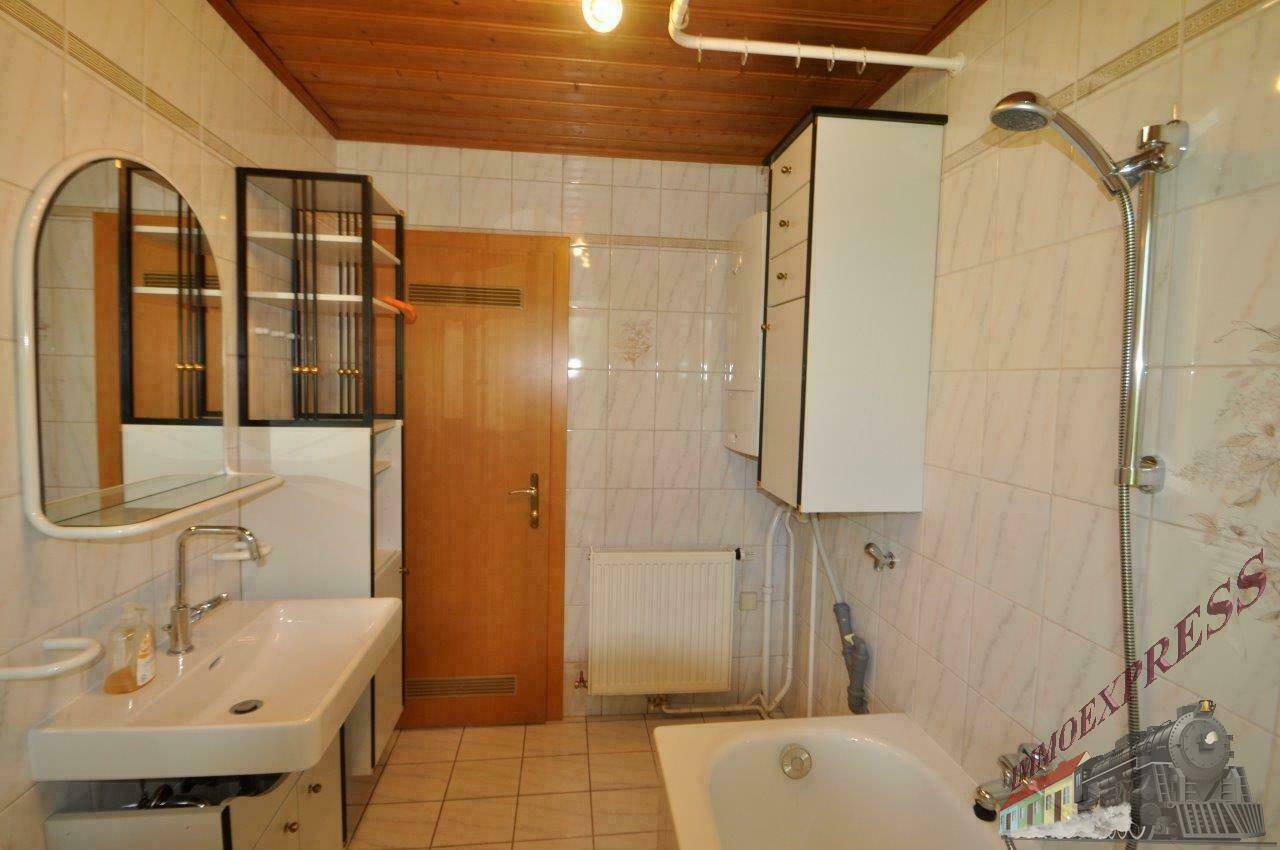 Funktionales Badezimmer mit Badewanne, Waschbecken, Spiegel und Holzdeckenverkleidung.