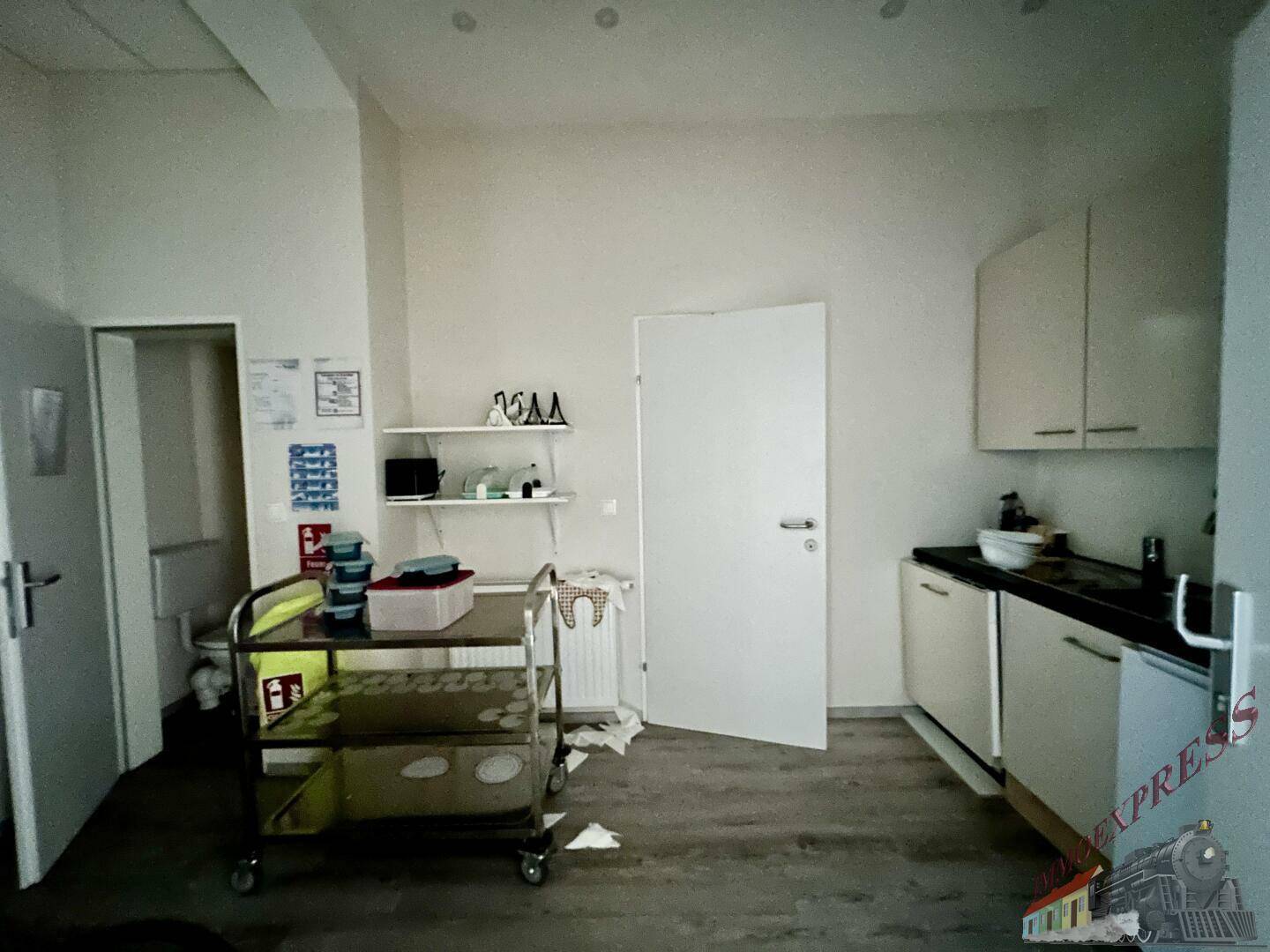 Kleine Küchenzeile mit weißen Schränken, dunkler Arbeitsplatte und Spülbecken, funktional eingerichtet.