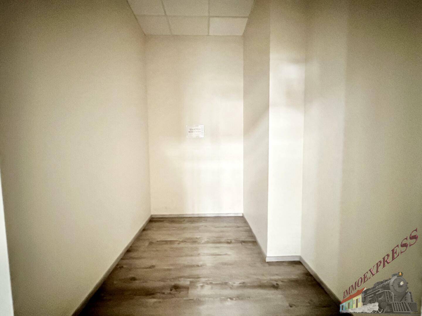 Leerer, schmaler Abstellraum mit dunklem Boden und weißen Wänden, bietet zusätzlichen Stauraum.