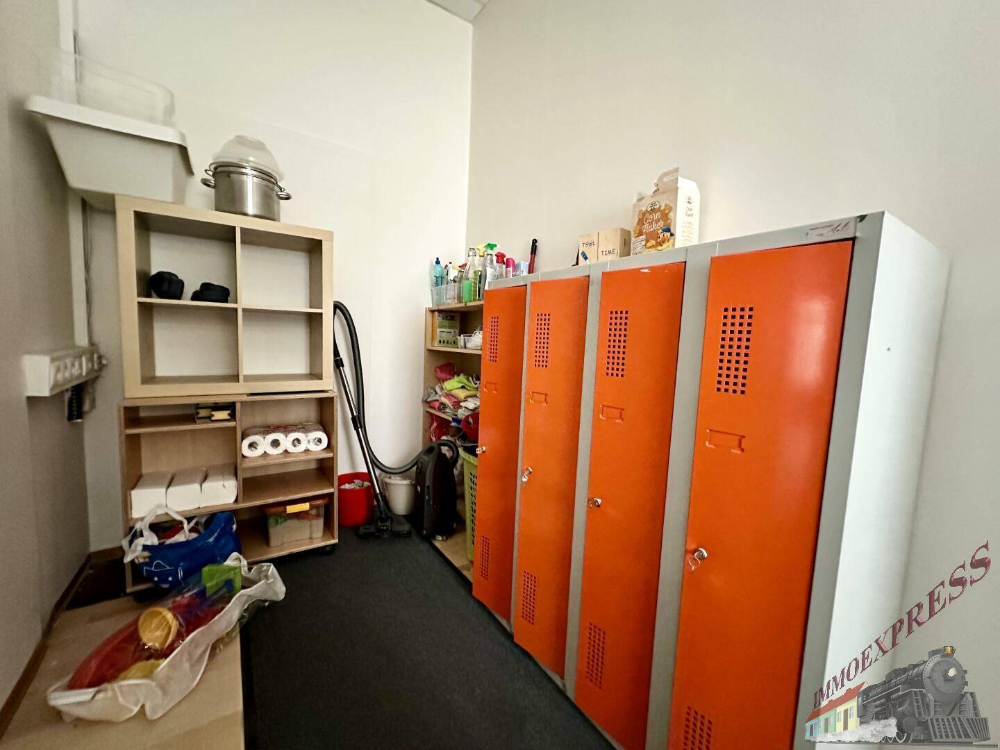 Funktionaler Hauswirtschaftsraum mit orangefarbenen Spinden, Regalen und Reinigungsutensilien, gut organisiert.