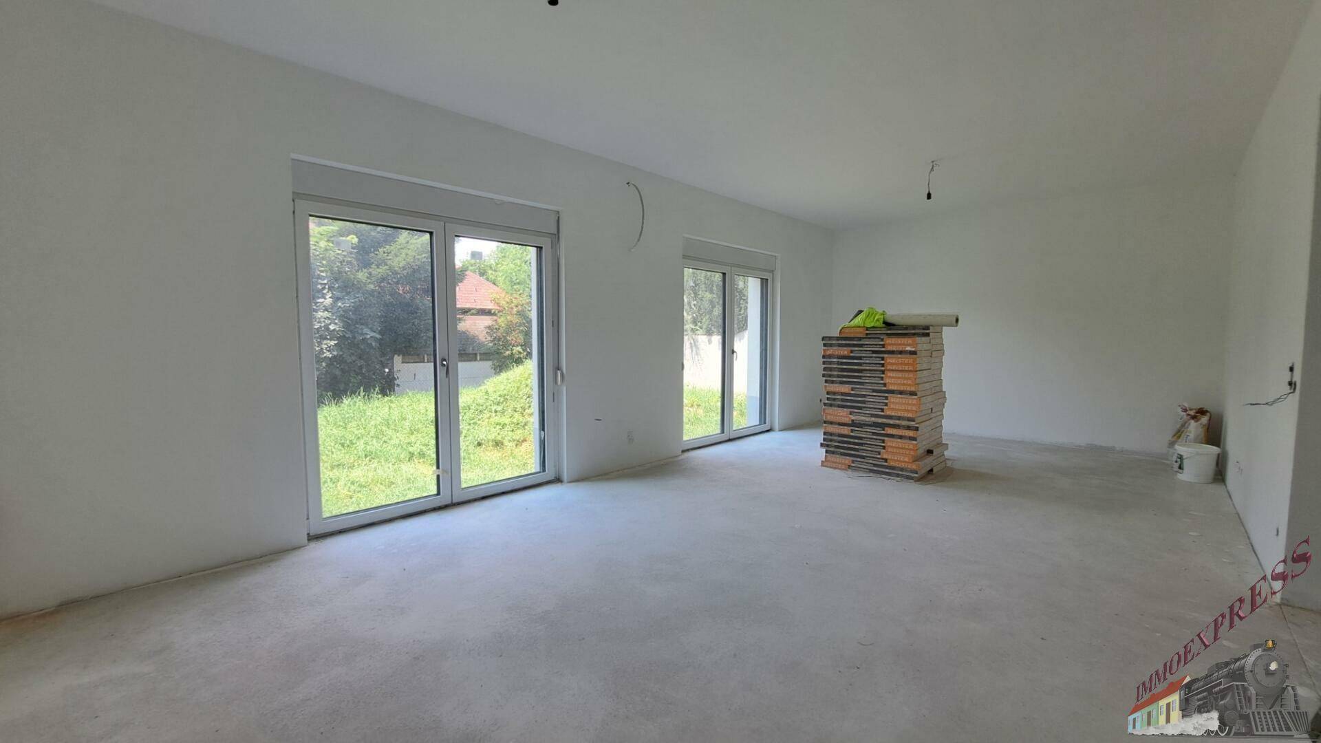 Heller Wohnraum mit zwei großen Terrassentüren und Blick in den Garten.