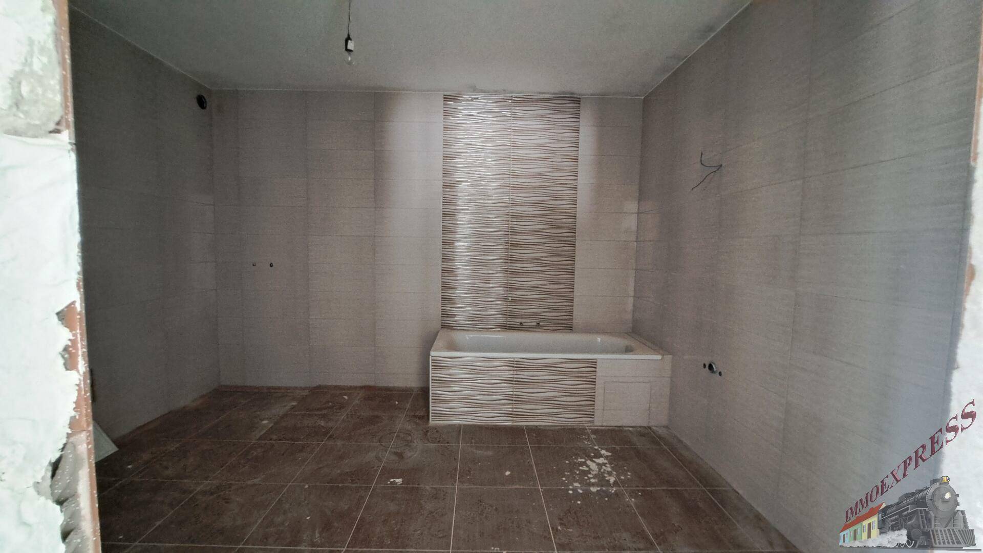 Modern gefliestes Badezimmer mit Badewanne und vorbereiteten Anschlüssen.
