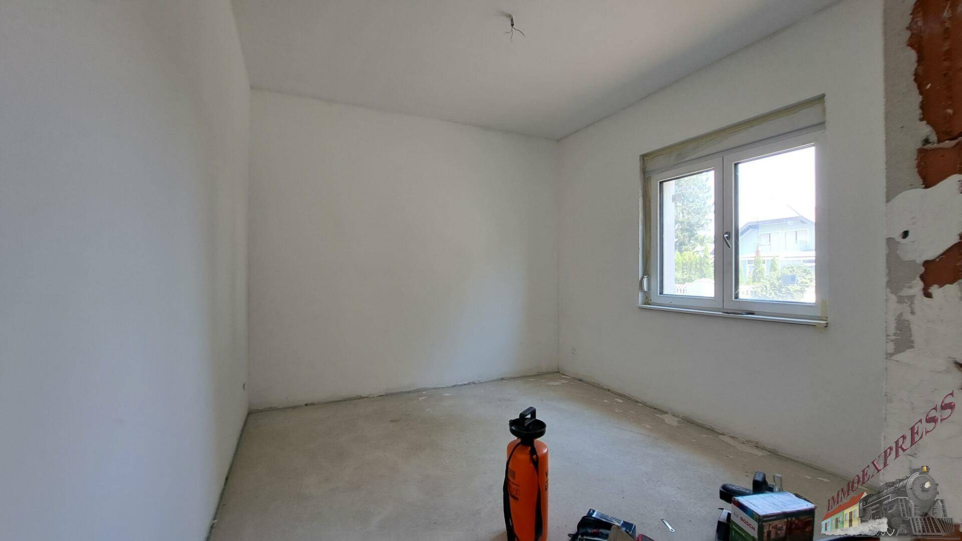 Helles Schlafzimmer im Rohbau mit Fenster und Baustellenmaterial.