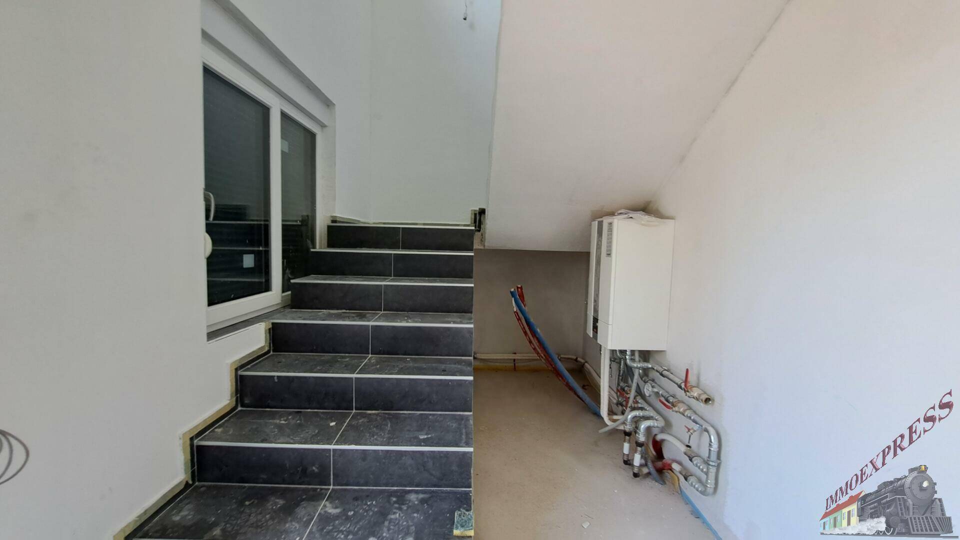 Technikraum unter der Treppe mit Heizungsanlage und sichtbaren Leitungen.
