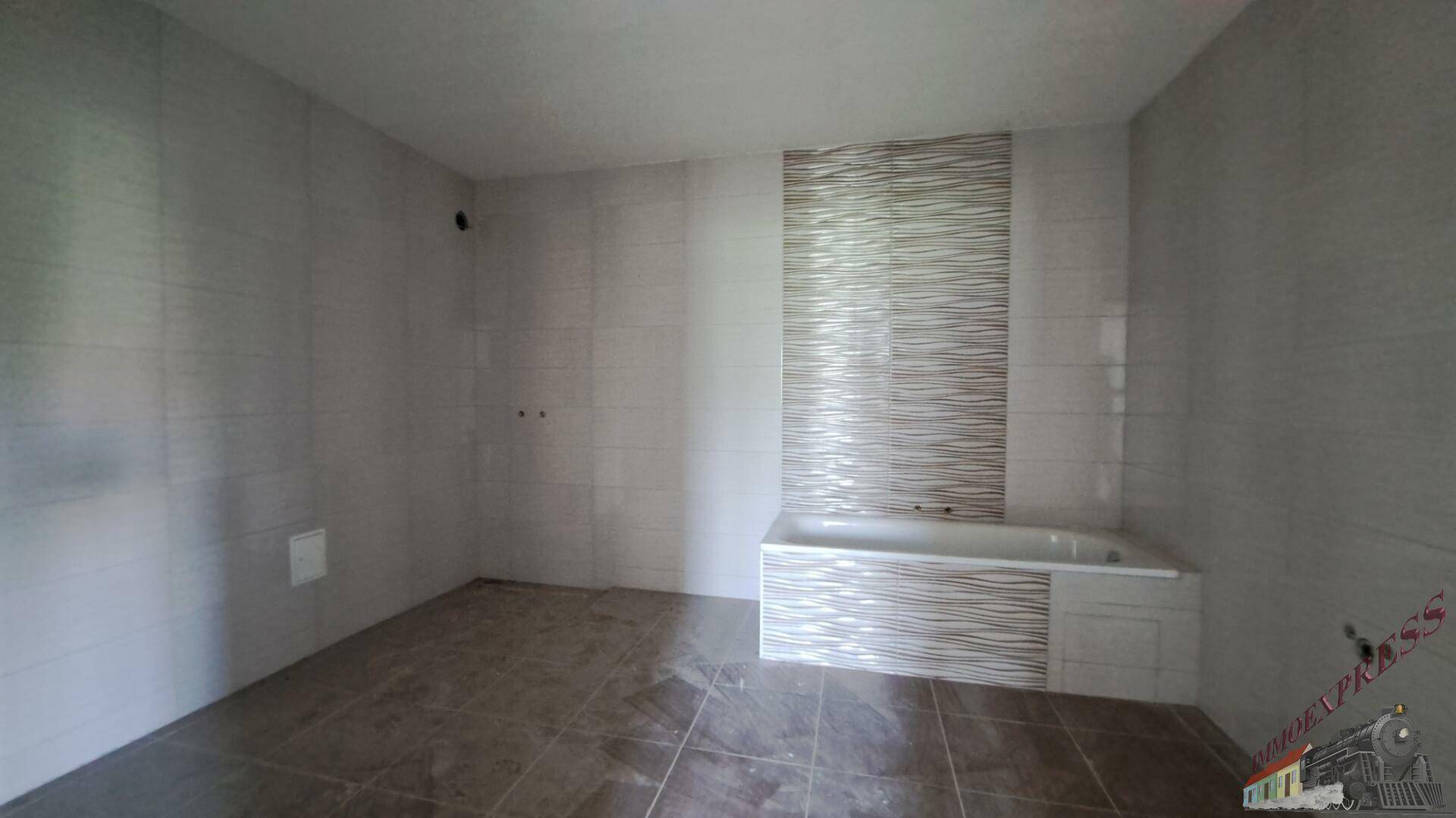 Modern gefliestes Badezimmer mit Badewanne und vorbereiteten Anschlüssen.